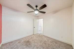 Carpeted spare room featuring ceiling fan and baseboards