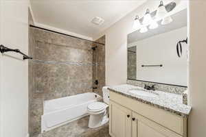 Full bathroom featuring a textured ceiling, vanity, toilet, and shower / bathtub combination