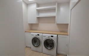 Laundry room with cabinet space, light wood-style flooring, and baseboards