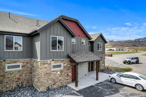 Craftsman-style house featuring board and batten siding, stone siding, uncovered parking, and a mountain view