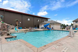 Waterdance Rec Center outside pool featuring fence, a water slide, and a patio