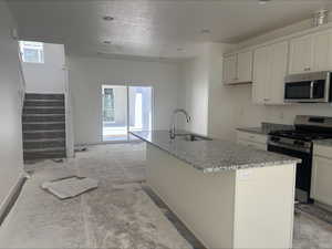 Kitchen with plenty of natural light, a sink, light stone counters, and stainless steel appliances