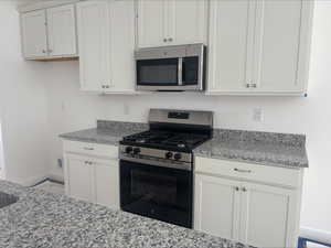 Kitchen featuring baseboards, appliances with stainless steel finishes, and light stone countertops