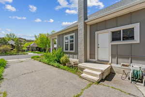 Property entrance featuring a chimney, board and batten siding, and a shingled roof