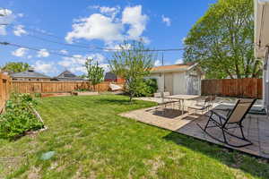 View of yard featuring an outbuilding, a vegetable garden, a fenced backyard, and a patio area
