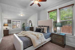 Carpeted bedroom featuring electric panel, baseboards, vaulted ceiling, and ceiling fan