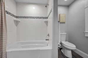Full bathroom featuring tile patterned flooring, shower / bath combination with curtain, toilet, and baseboards