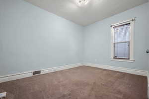 Spare room featuring carpet floors and baseboards