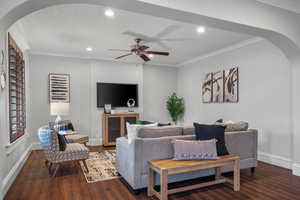 Living room with arched walkways, wood finished floors, recessed lighting, baseboards, and a ceiling fan