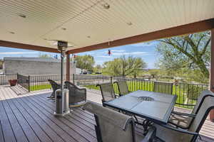 Wooden terrace featuring outdoor dining space and a yard
