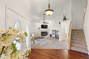 Foyer featuring stairway, ceiling fan, a healthy amount of sunlight, wood finished floors, and high vaulted ceiling
