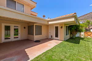 Back of house with a lawn, a patio area, stucco siding, and a mountain view