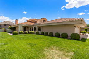 View of front of property with a front yard, an attached garage, a tiled roof, stucco siding, and fence
