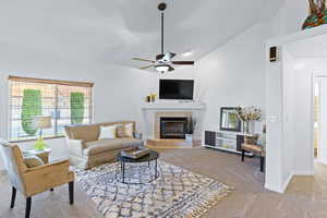 Living area with carpet flooring, a tiled fireplace, a ceiling fan, baseboards, and lofted ceiling