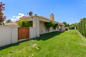 View of side of property featuring a lawn, stucco siding, a fenced backyard, and a chimney