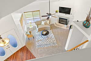 Living area featuring baseboards, a tile fireplace, vaulted ceiling, wood finished floors, and a ceiling fan
