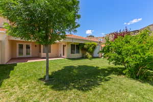 Back of house featuring stucco siding, a yard, french doors, and a tile roof