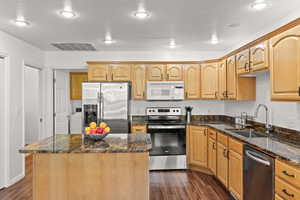 Kitchen featuring a textured ceiling, a sink, visible vents, stainless steel appliances, and dark wood finished floors