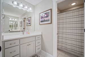 Bathroom featuring tile patterned floors, curtained shower, vanity, and baseboards