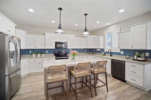 Kitchen with a sink, white cabinets, backsplash, and stainless steel appliances
