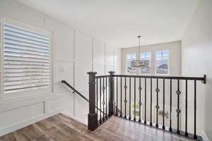 Stairway with wood finished floors, a decorative wall, and a notable chandelier
