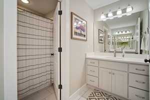 Full bathroom featuring vanity, a shower with shower curtain, tile patterned flooring, and baseboards
