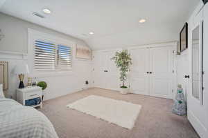 Carpeted bedroom with visible vents, recessed lighting, two closets, and vaulted ceiling