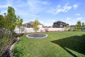 View of yard with a fenced backyard, a residential view, and a trampoline