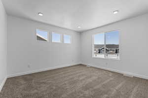Carpeted spare room featuring recessed lighting, visible vents, and baseboards