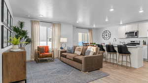 Living room with light wood-type flooring, a textured ceiling, and recessed lighting