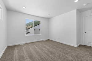 Carpeted spare room with baseboards, visible vents, and recessed lighting