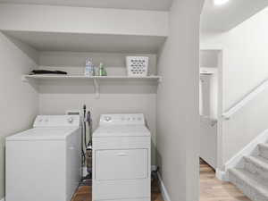 Washroom with light wood-style floors, washer and clothes dryer, laundry area, and baseboards