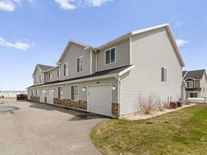 View of home's exterior featuring central air condition unit, a yard, an attached garage, and aphalt driveway