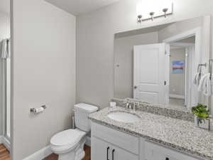 Bathroom featuring baseboards, wood finished floors, toilet, and vanity