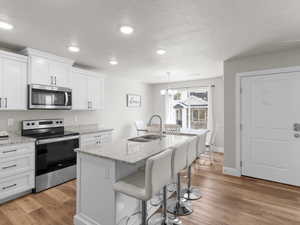 Kitchen featuring white cabinets, light wood-type flooring, appliances with stainless steel finishes, and a sink