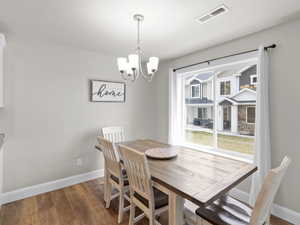 Dining room with an inviting chandelier, visible vents, light wood-style flooring, and baseboards