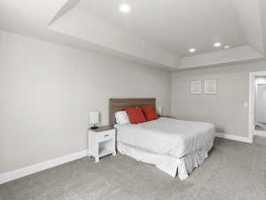 Bedroom featuring recessed lighting, light carpet, a raised ceiling, and baseboards