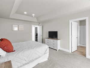 Bedroom with baseboards, recessed lighting, a raised ceiling, and light colored carpet