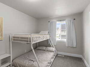 Carpeted bedroom featuring baseboards and visible vents