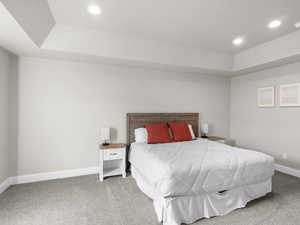 Carpeted bedroom featuring recessed lighting, a tray ceiling, and baseboards
