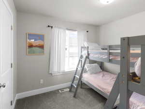 Bedroom with carpet, visible vents, baseboards, and multiple windows