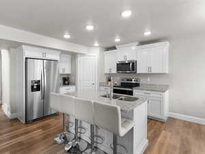 Kitchen featuring appliances with stainless steel finishes, white cabinets, light wood finished floors, and baseboards