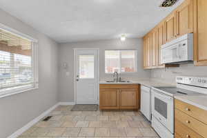 Kitchen featuring a wealth of natural light, visible vents, white appliances, and a sink