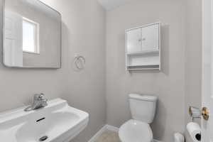 Bathroom featuring toilet, a sink, and baseboards