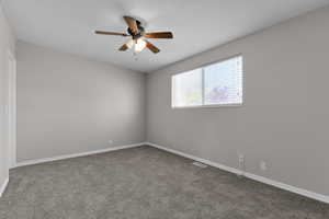 Empty room featuring a ceiling fan, carpet flooring, and baseboards