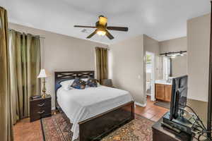 Bedroom featuring light tile patterned floors, visible vents, ensuite bathroom, baseboards, and a ceiling fan