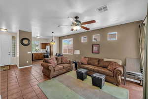 Living area with baseboards, visible vents, a ceiling fan, a textured ceiling, and light tile patterned flooring