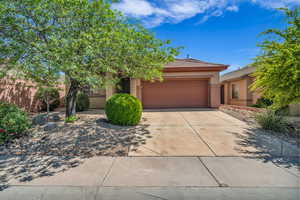 View of front of property featuring a tile roof, concrete driveway, a garage, and stucco siding