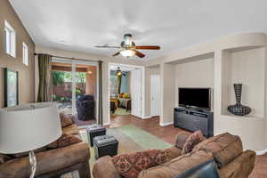 Living room with a textured ceiling, ceiling fan, tile patterned floors, and baseboards