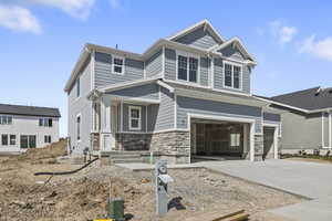 Craftsman house featuring driveway, an attached garage, and stone siding